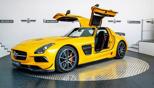 A yellow car with its doors open is standing on a turntable