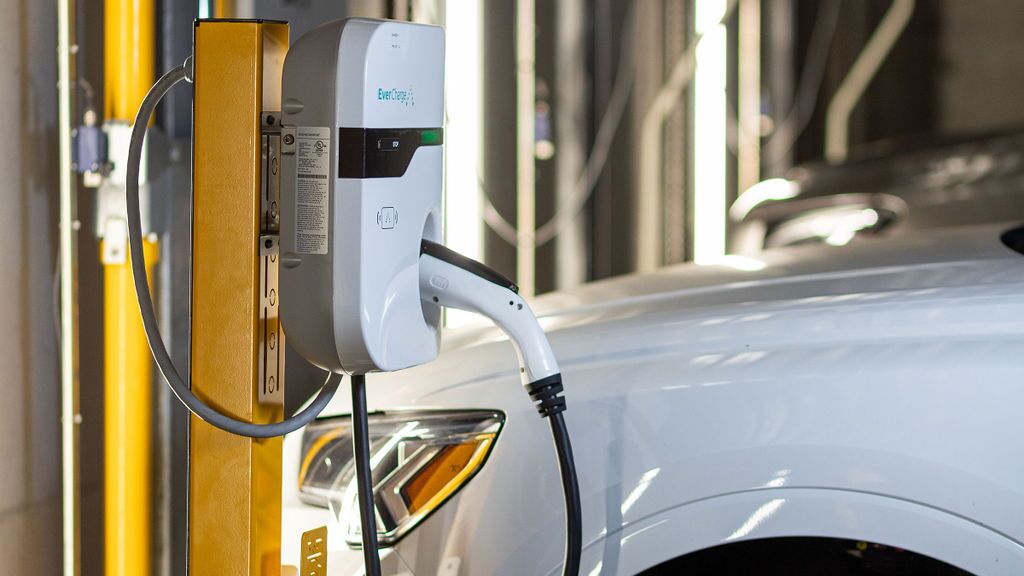 Un vehicul este parcat pe platforma unui sistem de parcare și este încărcat prin intermediul facilității integrate de încărcare pentru vehicule electrice.