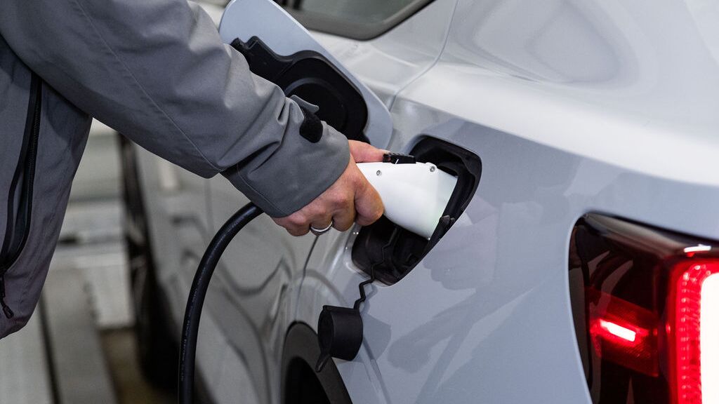 Imaginea prezintă procesul de încărcare a unui vehicul electric, în cadrul căruia un conector de încărcare este conectat la vehicul pentru a încărca bateria în timpul procesului de parcare.