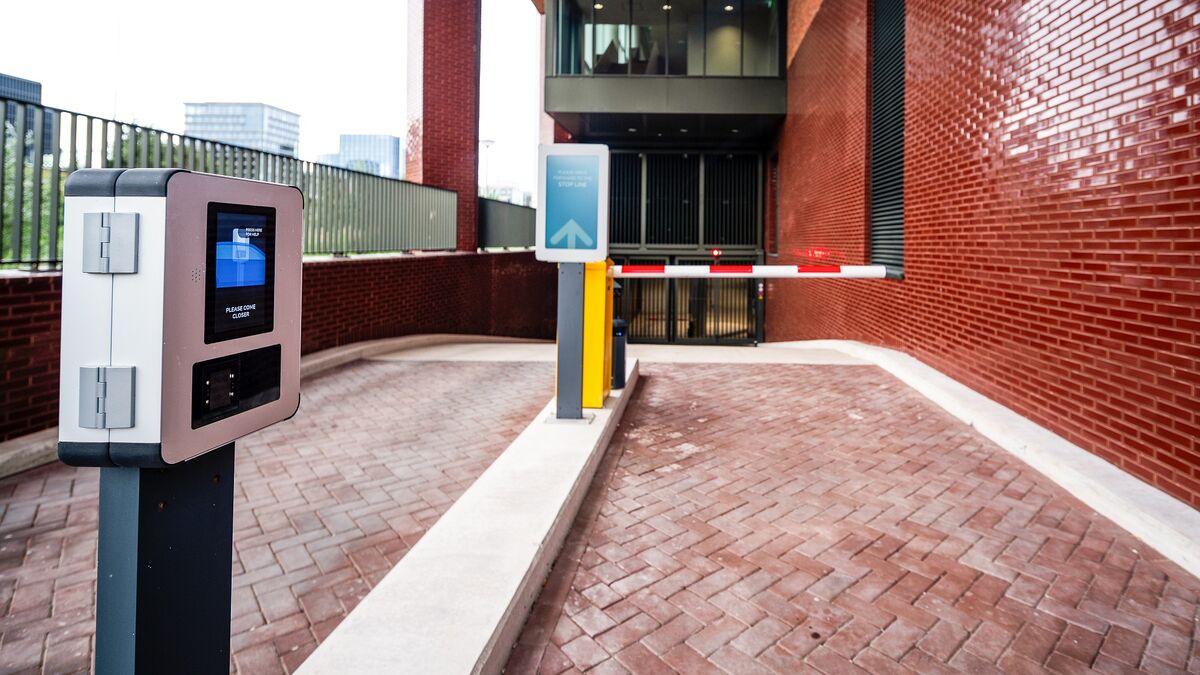 Entrance to a modern parking system with an access terminal, digital guidance system, and automatic barrier.